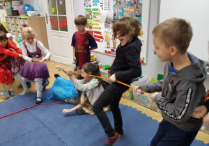 Dzieci bawią się w przeciąganie liny w sali przedszkolnej